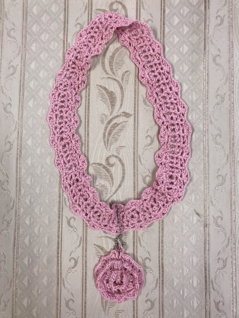 ピンク色の手編みの首飾りの画像。結城さんが作ったものです。